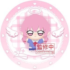 May include: A plush doll with pink hair, a halo, and white wings, wearing a blue shirt with a red bow. The doll is centered on a circular pink background with a white heart border and a white ribbon banner containing the text 監修中 confirming.