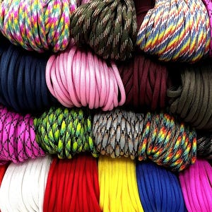 May include: A selection of brightly coloured paracord bundles, including pink, blue, green, yellow, and red. The cords are tightly wound and arranged to display a variety of patterns and colours. Each bundle is approximately 10 cm in diameter.