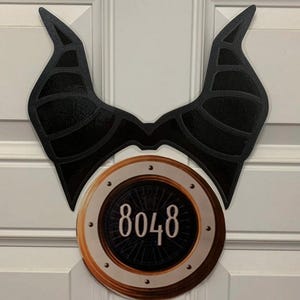 May include: Black and gold door hanger with a pair of black horns and a round gold circle with the number 8048 in the center.