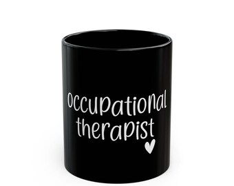 May include: Black ceramic coffee mug with white text that reads "occupational therapist" and a small white heart.
