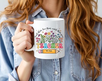 Op de afbeelding: Witte keramische mok met een kleurrijk bloemenontwerp en de tekst "Teach them, love them, watch them grow, TEACHER, Mrs. Davis".