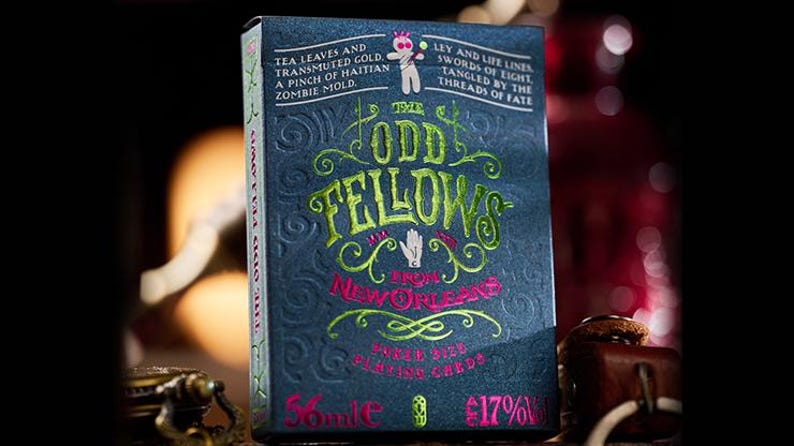 May include: A deck of playing cards with a dark blue background and green and pink text. The text reads "The Odd Fellows from New Orleans" and "Green Dye Playing Cards".