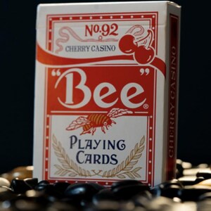 May include: A red and white deck of Bee playing cards with a bee illustration and the text "No. 92 Cherry Casino" and "Bee Playing Cards".
