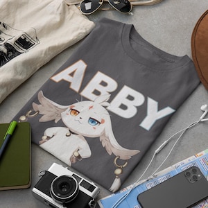 May include: A gray t-shirt with a white cartoon character and the name "Abby" printed in white.