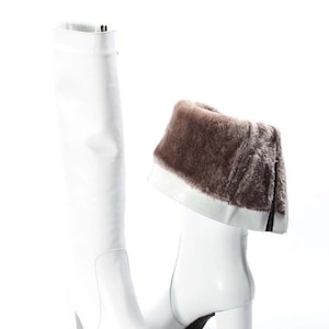 May include: White leather knee-high boots with a block heel and a brown faux fur trim around the top of the boot.