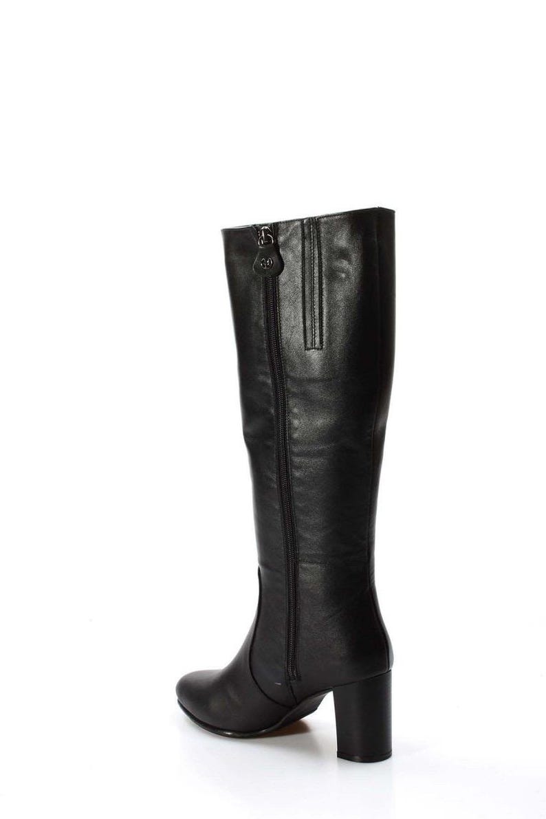 May include: Black leather knee-high boots with a block heel and a zipper up the back.