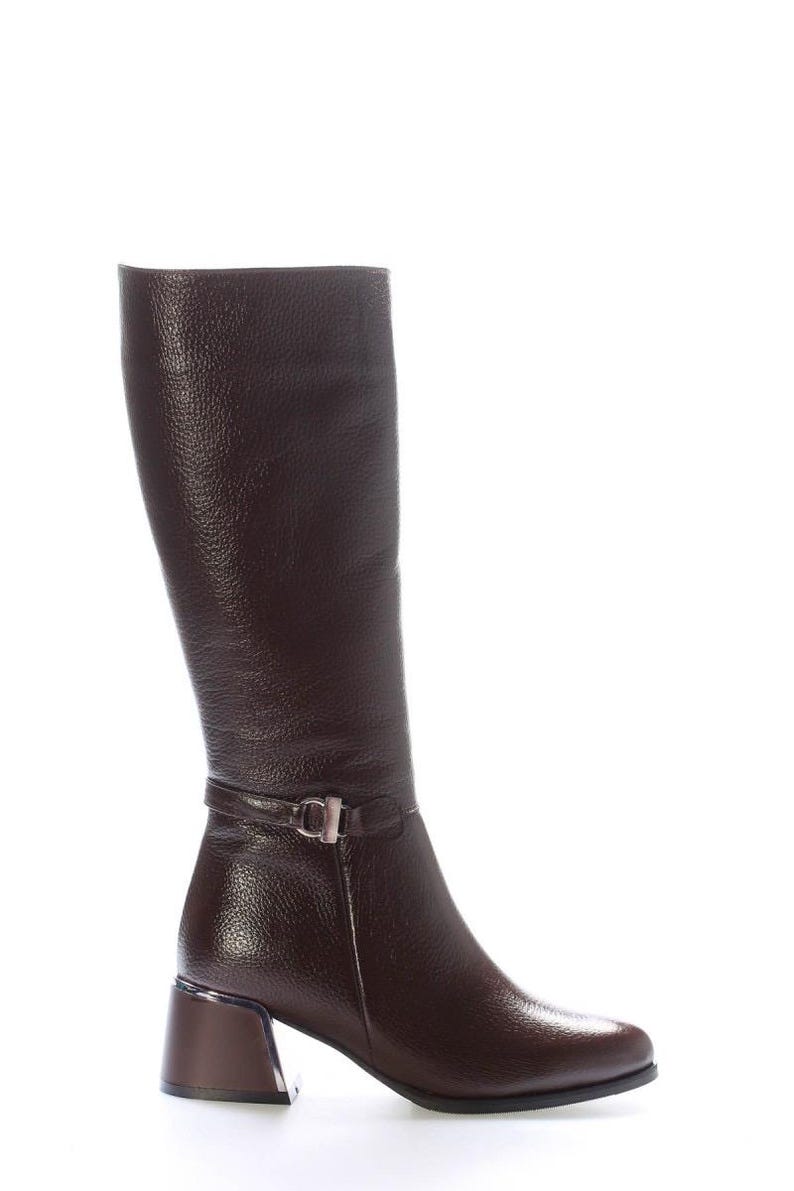 May include: A knee-high, dark brown leather boot with a textured finish. The boot features a small strap with a silver buckle around the ankle and a block heel. The heel measures approximately 5 cm.