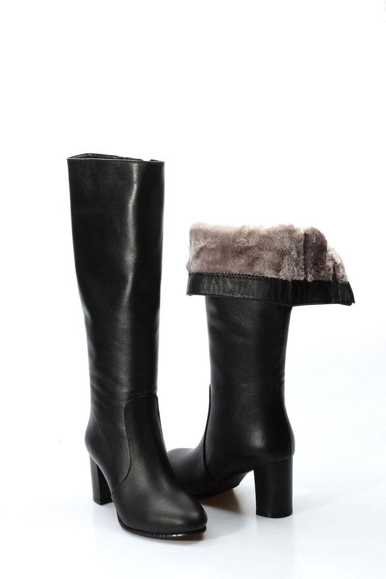 May include: A pair of black leather knee-high boots with a block heel. The boots have a faux fur lining and a fold-over top.