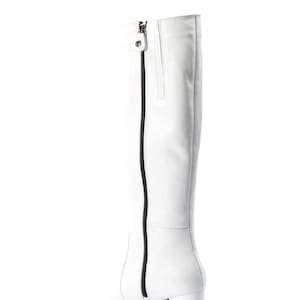 May include: White leather knee-high boots with a black zipper up the back and a block heel.