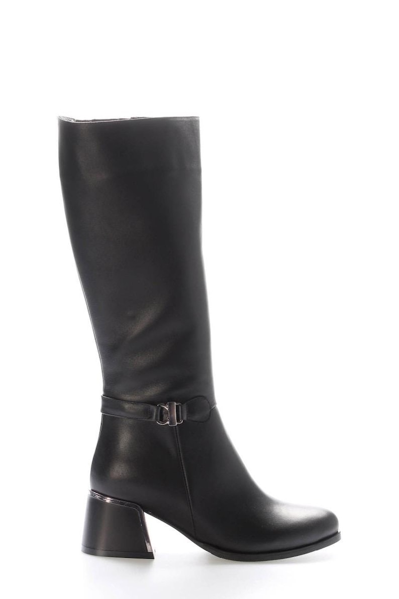 May include: Black knee-high boot with a square toe and a block heel. The boot features a strap with a silver-tone buckle detail around the ankle. The heel is approximately 7.6 cm high. The boot is made of a smooth, solid black material.