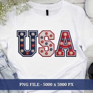 Può includere: T-shirt bianco con la scritta "USA" ricamata con motivi floreali rossi, bianchi e blu. Le lettere sono delineate in blu navy e rosso, creando un design patriottico. La maglietta è realizzata in un materiale morbido e confortevole.