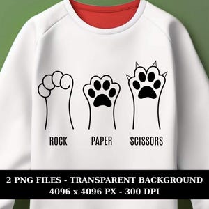 May include: White sweatshirt with a red collar featuring a black and white graphic of Rock, Paper, Scissors using paw prints. The text "ROCK", "PAPER", and "SCISSORS" is below each paw print. The bottom of the image has text that reads "2 PNG FILES - TRANSPARENT BACKGROUND 4096 x 4096 PX - 300 DPI".