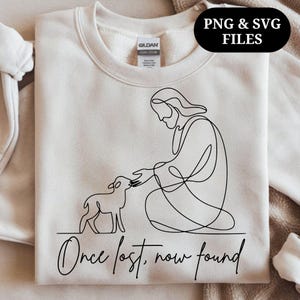 Op de afbeelding: Crèmekleurige sweatshirt met een zwarte lijntekening van een figuur die een lam aanraakt. De tekst "Once lost, now found" staat eronder. De rechterbovenhoek heeft de tekst "PNG & SVG FILES" in een zwart ovaal.