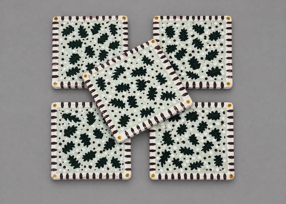 Hand-painted ceramic Christmas coasters with leaves and berries — genuine ceramics craft, whimsical holiday art, and at $85 for a set of 5 this is artisan pricing that signals real skill.