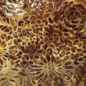 May include: Abstract art print featuring a swirling pattern of gold and brown colors. The pattern resembles a close-up of a natural texture, like a rock or a piece of wood.