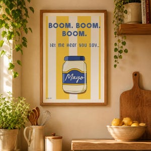 May include: A framed wall art print featuring a yellow and white vertical striped background. The text reads BOOM. BOOM. BOOM. let me hear you say... above a graphic illustration of a glass jar with a blue lid and a label that says Mayo.