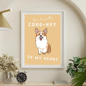 May include: Framed art print featuring a cartoon corgi dog with the text "You have the CORG-KEY to my heart" on a yellow background. The corgi is brown, white, and tan. The print is in a white frame.
