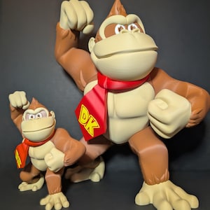 May include: Two 3D printed Donkey Kong figures, one large and one small, both with red scarves and the letters "DK" on their chests. The figures are posed with their fists clenched.