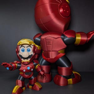 May include: Two red and gold action figures, one large and one small, resembling a mashup of Mario and Iron Man. The figures have a metallic finish, with black accents and yellow highlights. The smaller figure is in front of the larger one.