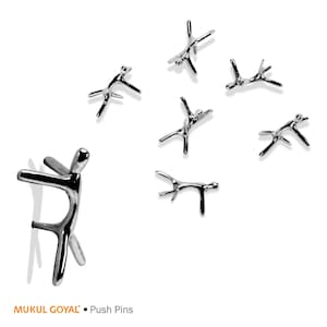 May include: A set of seven silver push pins shaped like stylized human figures. The push pins are arranged in a scattered pattern on a white background. The text "MUKUL GOYAL" and "Push Pins" is visible at the bottom of the image.
