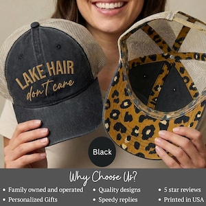 May include: A charcoal gray trucker hat with a tan mesh back and the text LAKE HAIR don't care embroidered in gold on the front. A second hat is shown from the inside, featuring a brown and black leopard print pattern on the underside of the brim.
