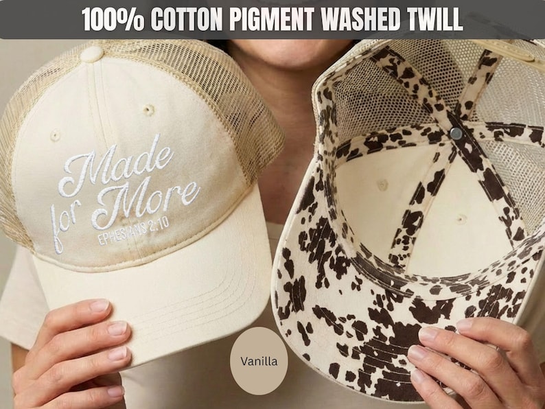 May include: A vanilla-colored trucker hat made of 100% cotton pigment washed twill. The front features white embroidered text reading Made for More Ephesians 2:10. The hat has a mesh back and an interior lining with a brown and white cow print pattern.