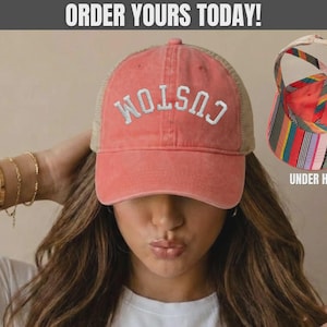 May include: A sherbet-colored baseball cap with a mesh back and the word CUSTOM embroidered in white on the front. An inset shows the underside of the hat, which features a colorful vertical striped pattern and a crisscross strap design.