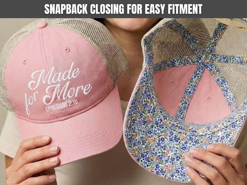 May include: A pink trucker hat with a beige mesh back and a snapback closure. The front features white embroidered text reading Made for More EPHESIANS 2:10. The interior lining of the hat displays a blue, pink, and green floral pattern.