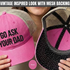 K&ouml;nnte beinhalten: Zwei pinkfarbene Trucker-Caps mit Mesh-R&uuml;cken werden gezeigt. Eine Kappe tr&auml;gt den schwarzen Text "GO ASK YOUR DAD". Die andere Kappe ist auf links gedreht und zeigt ein schwarzes Innenfutter mit wei&szlig;en Punkten. Die Kappen haben einen Vintage-Look.