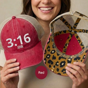 May include: Red trucker hat with the text "3:16 JOHN" in white. The hat has a mesh back and a leopard print pattern on the underside of the brim. The hat is red.