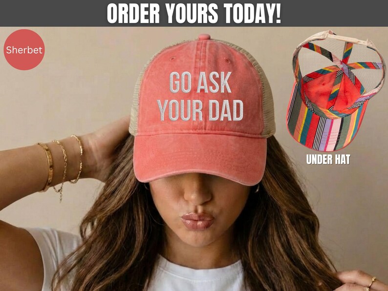 K&ouml;nnte beinhalten: Korallenfarbene Trucker-M&uuml;tze mit dem Text "GO ASK YOUR DAD" in Wei&szlig;. Die M&uuml;tze hat einen Mesh-R&uuml;cken und einen gebogenen Schirm. Das Bild zeigt auch eine bunt gestreifte Unterkappe.
