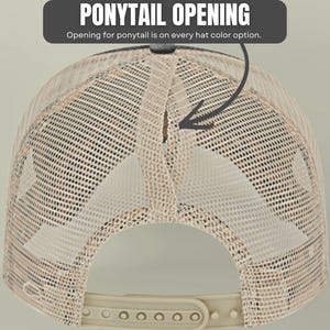 May include: A beige mesh trucker hat featuring a vertical ponytail opening at the back. The text PONYTAIL OPENING and Opening for ponytail is on every hat color option is displayed above the hat with an arrow pointing to the opening.