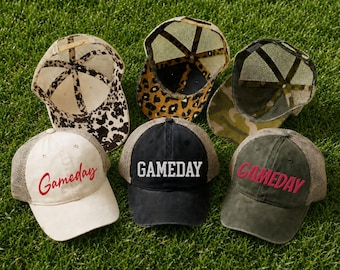 May include: A collection of six trucker hats featuring mesh backs and various front panels. Three hats display the word Gameday in different fonts and colors, while the others feature cow print, leopard print, and camouflage patterns respectively.