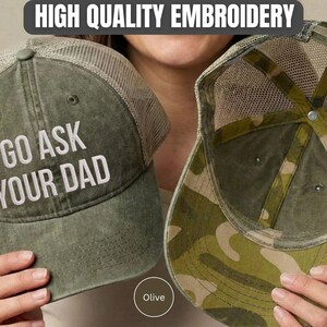 K&ouml;nnte beinhalten: Olivgr&uuml;ne Trucker-Cap mit dem wei&szlig;en gestickten Text "GO ASK YOUR DAD". Die Cap hat einen Mesh-R&uuml;cken und ein Camouflage-Muster auf der Unterseite des Schirms. Der Text "HIGH QUALITY EMBROIDERY" ist ebenfalls enthalten.