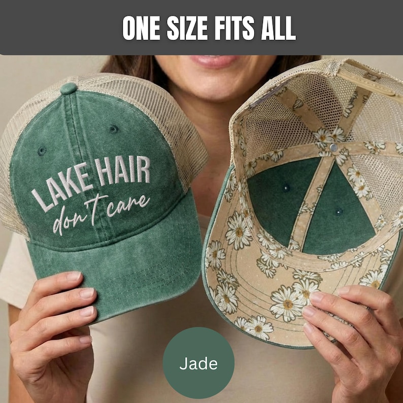 May include: A green trucker hat with a mesh back and the text "LAKE HAIR don't care" embroidered in white on the front. The interior of the hat features a white daisy floral pattern on a tan background. The text "ONE SIZE FITS ALL" is visible.