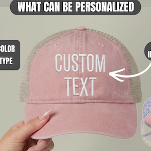 May include: A dusty pink baseball cap with a mesh back and white embroidered text that reads CUSTOM TEXT. The cap features a structured front panel and a curved brim. A small inset shows the interior lining with a floral pattern on the crown.