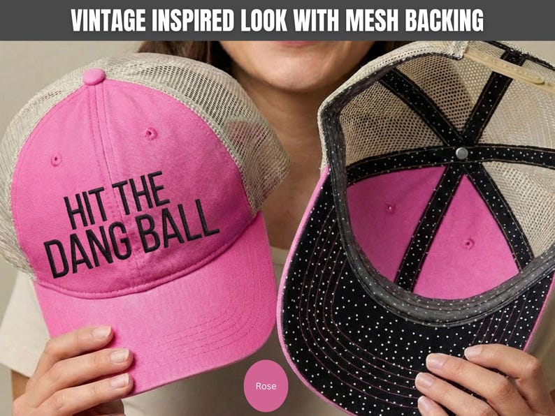 May include: A bright pink baseball cap with a beige mesh back and the text HIT THE DANG BALL embroidered in black on the front. The interior of the cap features a black lining with white polka dots and a pink crown, with a vintage inspired look.