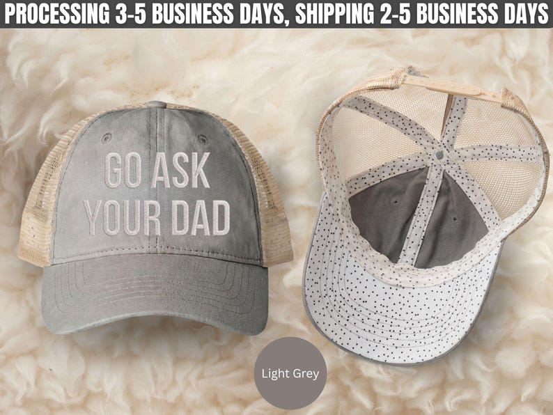 K&ouml;nnte beinhalten: Zwei hellgraue Trucker-Caps. Auf einer Kappe ist der Text "GO ASK YOUR DAD" wei&szlig; gestickt. Die andere Kappe ist nach innen gedreht und zeigt das Innendesign. Die Kappen haben einen Mesh-R&uuml;cken und einen gebogenen Schirm. Die Farbe der Kappe ist hellgrau.