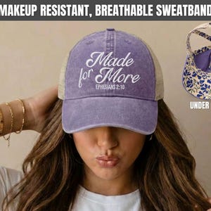 May include: A violet baseball cap with a mesh back and the white embroidered text Made for More EPHESIANS 2:10 on the front. The hat features a cutout design at the back and an interior lining with a blue and white floral pattern.