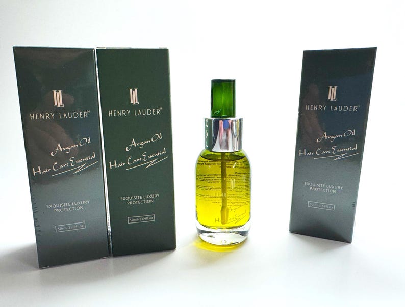 Puede incluir: Tres botellas de aceite de arg&aacute;n para el cuidado esencial del cabello con el nombre de la marca Henry Lauder impreso en la parte delantera. Las botellas son verdes y tienen una etiqueta dorada con texto blanco. El texto de la etiqueta dice "Argan Oil Hair Care Essential" y "Exquisite Luxury Protection".