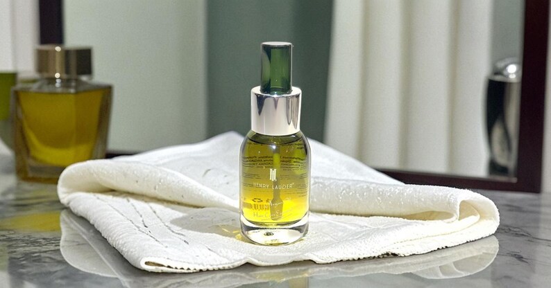 Puede incluir: Una botella de vidrio transparente con un gotero verde y una tapa plateada. La botella est&aacute; llena de un l&iacute;quido amarillo y tiene el texto "MIRY LAUDER" impreso en la etiqueta.