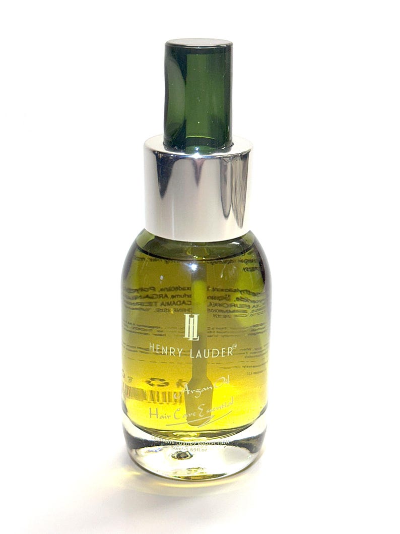 Puede incluir: Una botella de vidrio transparente con una tapa plateada y un gotero verde. La botella contiene un l&iacute;quido amarillo y tiene el texto "Henry Lauder" y "Argan Oil Hair Conditioner" impreso en la etiqueta.