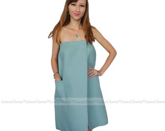 May include: A light blue wrap towel with a pocket. The towel is made of a soft, absorbent material and is perfect for drying off after a shower or bath.