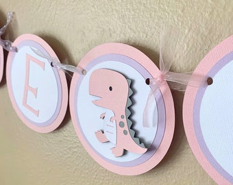 Verjaardagsbanner met dinosaurusmotief voor een meisje, roze decoratie voor een babyshower.