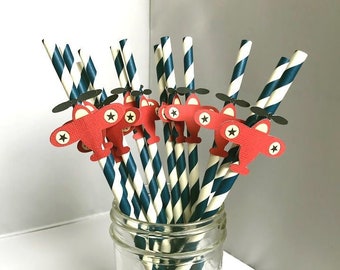 May include: A set of red and black paper straws with airplane cutouts. The straws are striped in white and navy blue and are in a clear glass jar.