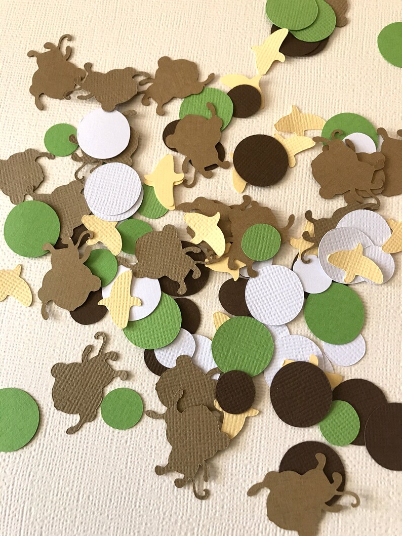 May include: A collection of brown, green, white, and yellow paper confetti. The confetti is in the shape of circles and small animals.