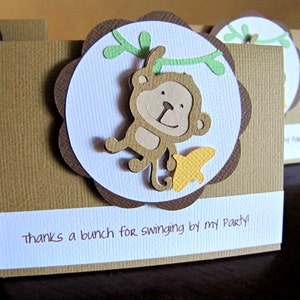 May include: Brown and white thank you card with a brown monkey hanging from a green vine. The monkey is holding a yellow star. The card says "thanks a bunch for swinging by my party!"