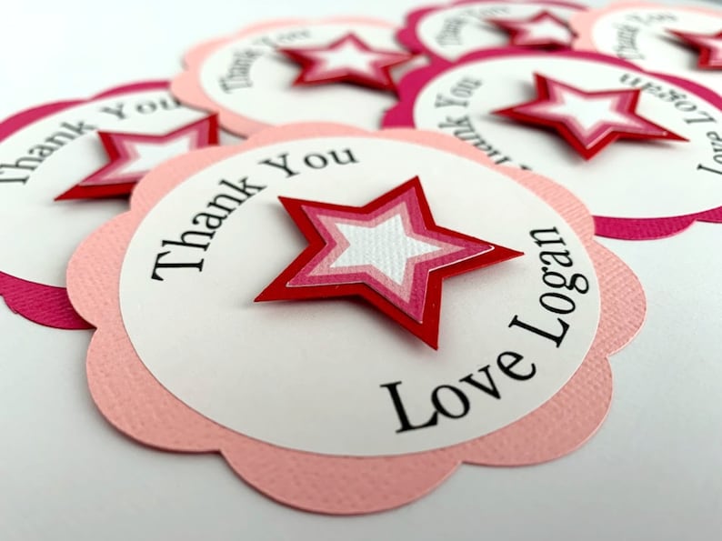 May include: Pink and white scalloped circle thank you tags with a red, pink, and white layered star. The text reads "Thank You Love Logan".