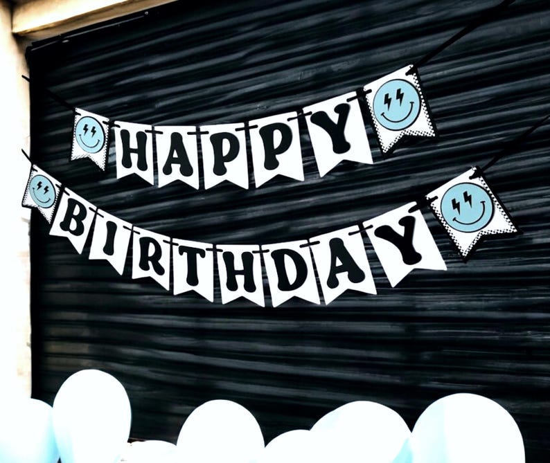 May include: White banner with black letters spelling "Happy Birthday" with blue and white smiley faces with lightning bolts on each end.