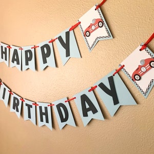 May include: A blue and white banner with the words "Happy Birthday" in black letters. The banner is decorated with red race cars.